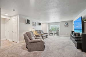 Carpeted living area featuring a textured ceiling and baseboards