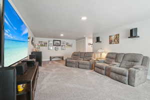 Carpeted living room featuring a textured ceiling, recessed lighting, and baseboards