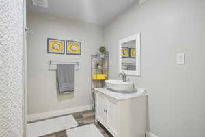 Full bathroom with baseboards, visible vents, wood finished floors, and vanity