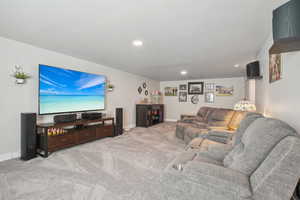 Carpeted living area with recessed lighting and baseboards