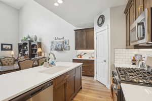 Kitchen with light wood finished floors, a sink, stainless steel appliances, and light countertops
