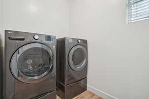 Laundry area with washer and dryer, light wood-style flooring, laundry area, and baseboards
