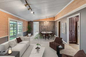 Living room with track lighting, lofted ceiling, baseboards, a notable chandelier, and crown molding