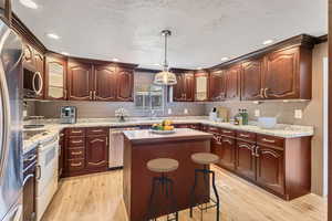 Kitchen featuring a center island, light wood-style flooring, hanging light fixtures, and appliances with stainless steel finishes