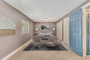 Bedroom featuring baseboards, light carpet, a textured ceiling, and two closets