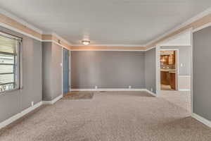 Carpeted spare room with baseboards and crown molding