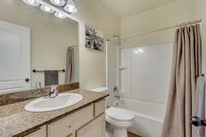 Bathroom with toilet, vanity, and shower / tub combo with curtain