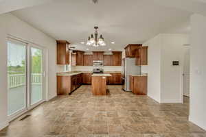 Kitchen with an inviting chandelier, visible vents, a center island, baseboards, and appliances with stainless steel finishes