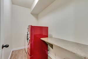 Washroom with light wood-style floors, baseboards, laundry area, and washer / clothes dryer