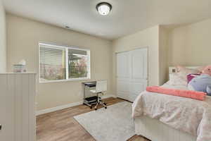 Bedroom #4  featuring light wood finished floors, baseboards, visible vents, and a closet