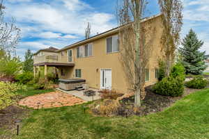 Back of property with a wooden deck, a patio area, a hot tub, a yard, and stucco siding