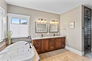 Bathroom with double vanity, oversized jetted tub, a sink, and baseboards