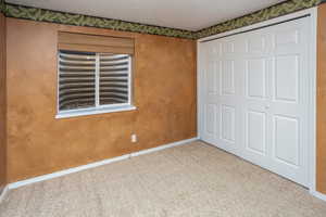 Unfurnished bedroom featuring baseboards, carpet flooring, and a closet