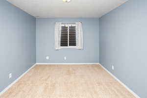 Carpeted spare room featuring baseboards