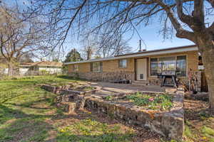 Rear view of property with a lawn, brick siding, fence, and a patio area