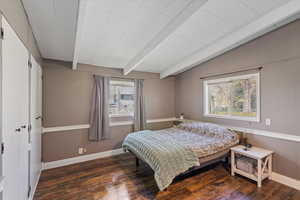 Bedroom featuring vaulted ceiling with beams, wood finished floors, and multiple windows