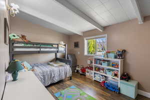 Bedroom with wood-type flooring and vaulted ceiling with beams