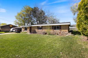 View of front facade with driveway, a front yard, and an attached carport