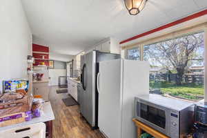 Kitchen with dark wood-type flooring, appliances with stainless steel finishes, and white cabinetry