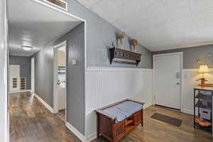 Corridor featuring wood finished floors, visible vents, and a wainscoted wall