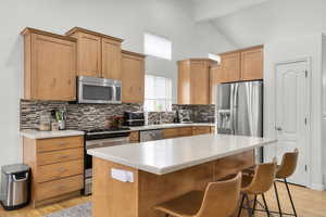 Kitchen featuring stainless steel appliances, light countertops, beam ceiling, and large island