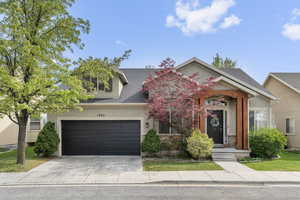 View of front facade featuring a garage, a shingled roof, driveway, and stucco siding