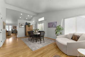 Dining room with lofted ceiling with beams, a wealth of natural light, and view into kitchen/living area.
