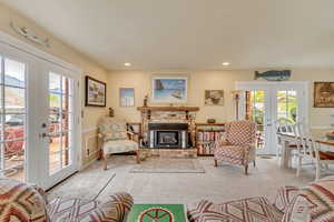 Carpeted living area with a fireplace, wainscoting, recessed lighting, and french doors