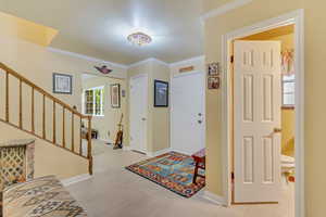 Foyer entrance featuring stairway, baseboards, ornamental molding, and light wood finished floors