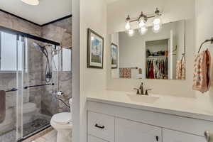 Full bath featuring a shower stall, toilet, and vanity