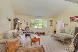 Living area with vaulted ceiling, baseboards, and carpet floors