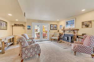 Living room featuring french doors, carpet flooring, recessed lighting, and a brick fireplace