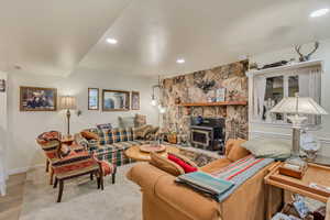 Living room featuring baseboards, a wood stove, and recessed lighting