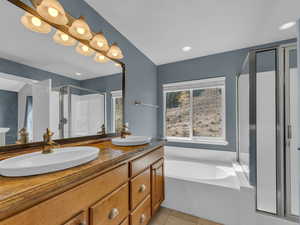 Bathroom with tile patterned floors, a sink, double vanity, and a stall shower