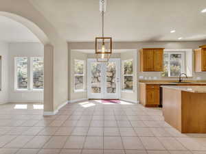 Kitchen featuring recessed lighting, light stone counters, a sink, arched walkways, and brown cabinetry