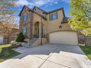 Traditional-style house with driveway, stone siding, and stucco siding
