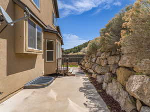 View of side of property featuring a patio area, stucco siding, and fence
