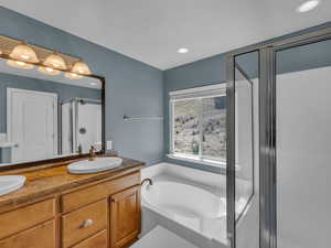 Bathroom featuring a sink, double vanity, recessed lighting, a shower stall, and a garden tub
