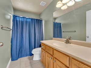 Full bath featuring toilet, visible vents, tile patterned flooring, a shower with shower curtain, and vanity