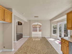 Unfurnished dining area with visible vents, light tile patterned floors, arched walkways, baseboards, and a notable chandelier