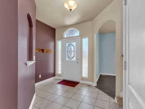 Entrance foyer with arched walkways, visible vents, baseboards, and light tile patterned floors