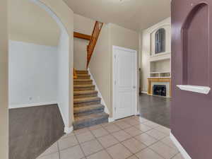 Stairway with arched walkways, a tile fireplace, built in features, and baseboards