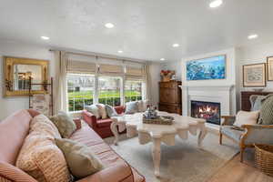 Living room featuring crown molding, a glass covered fireplace, light wood-type flooring, and recessed lighting