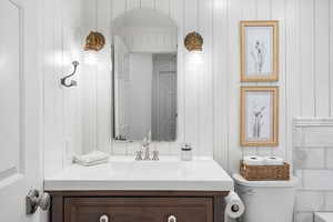 Bathroom with toilet, vanity, and a decorative wall