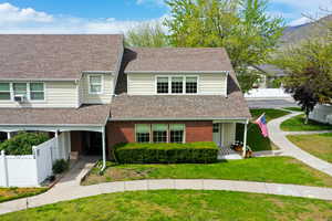 Townhome / multi-family property with cooling unit, fence, brick siding, a shingled roof, and a front yard