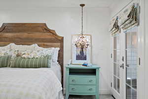 Bedroom featuring baseboards, ornamental molding, french doors, and a chandelier