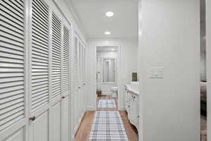 Hall featuring baseboards, crown molding, light wood finished floors, and recessed lighting