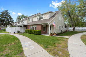 Traditional home featuring brick siding, roof with shingles, a front lawn, and fence