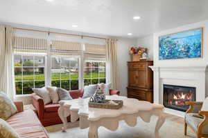 Interior space with a healthy amount of sunlight, a glass covered fireplace, crown molding, and recessed lighting