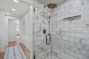 Full bathroom featuring recessed lighting, wood finished floors, a stall shower, and ornamental molding